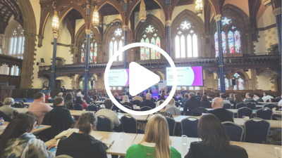 A photo of the Child Poverty and Public Debt Crisis conference with a play button symbol