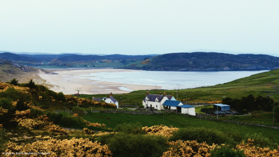 A photo of Bettyhill, Thurso, there are houses in the foreground and a sea bay in the background