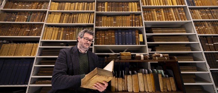 Professor Adrian Streete looking at a book from the personal library of Zachary Boyd held in the University’s Archives & Special Collections. Credit Martin Shields.