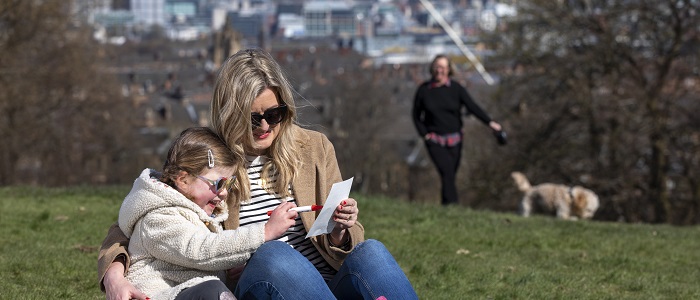 Emma Gilmartin and daughter Millie from Glasgow sitting in the park as Rafa the dog is being walked by  Professor Deirdre Heddon of the University of Glasgow who is leading the Covid Walking Project. Photo credit Martin Shields